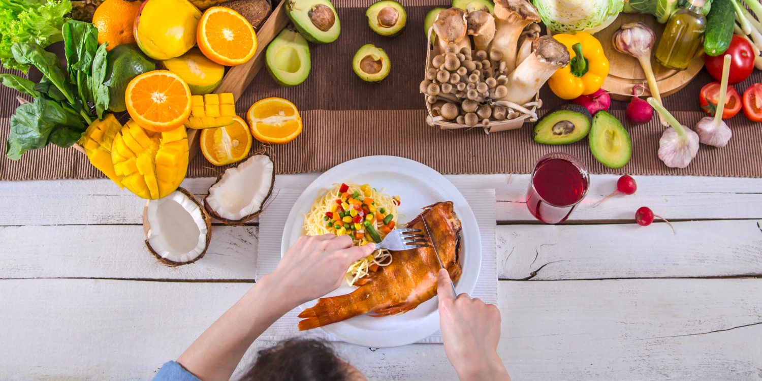 Woman at the dining table with a variety of organic healthy food , top view. The concept of healthy eating and celebration